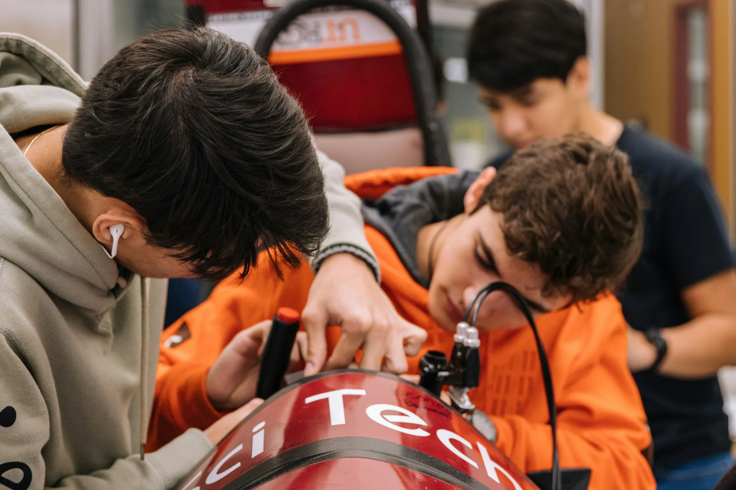Teenage students working together on a robot build in a school workshop