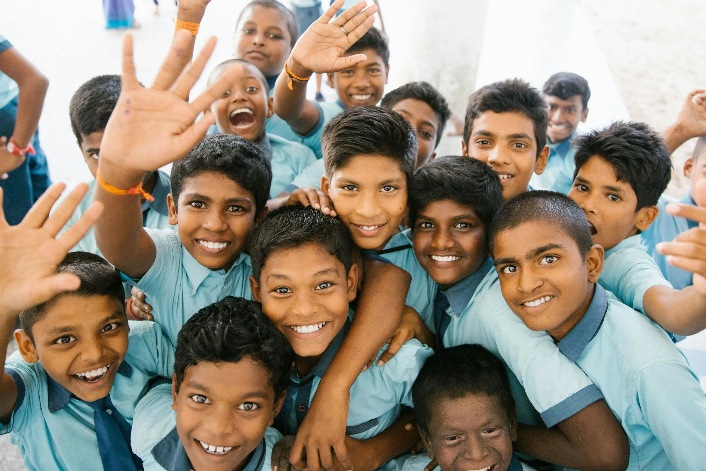 A cheerful group of Indian schoolchildren in blue uniforms waving at the camera