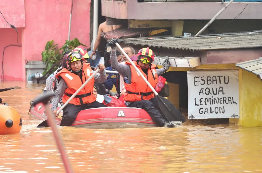 Rescuers in life jackets paddling a raft along a flooded street
